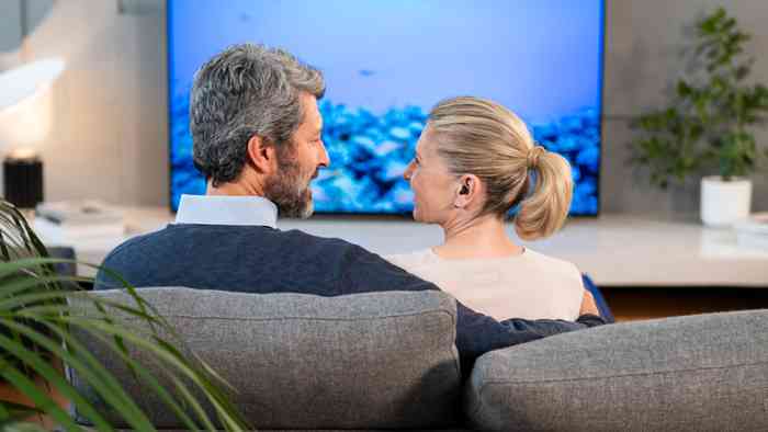 Casal desfruta de momento a ver um filme com o som da TV diretamente nos aparelhos auditivos