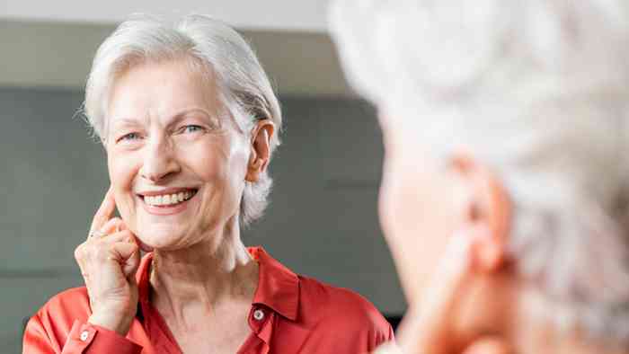 Mulher a colocar a mão no ouvido onde tem um aparelho auditivo da Minisom