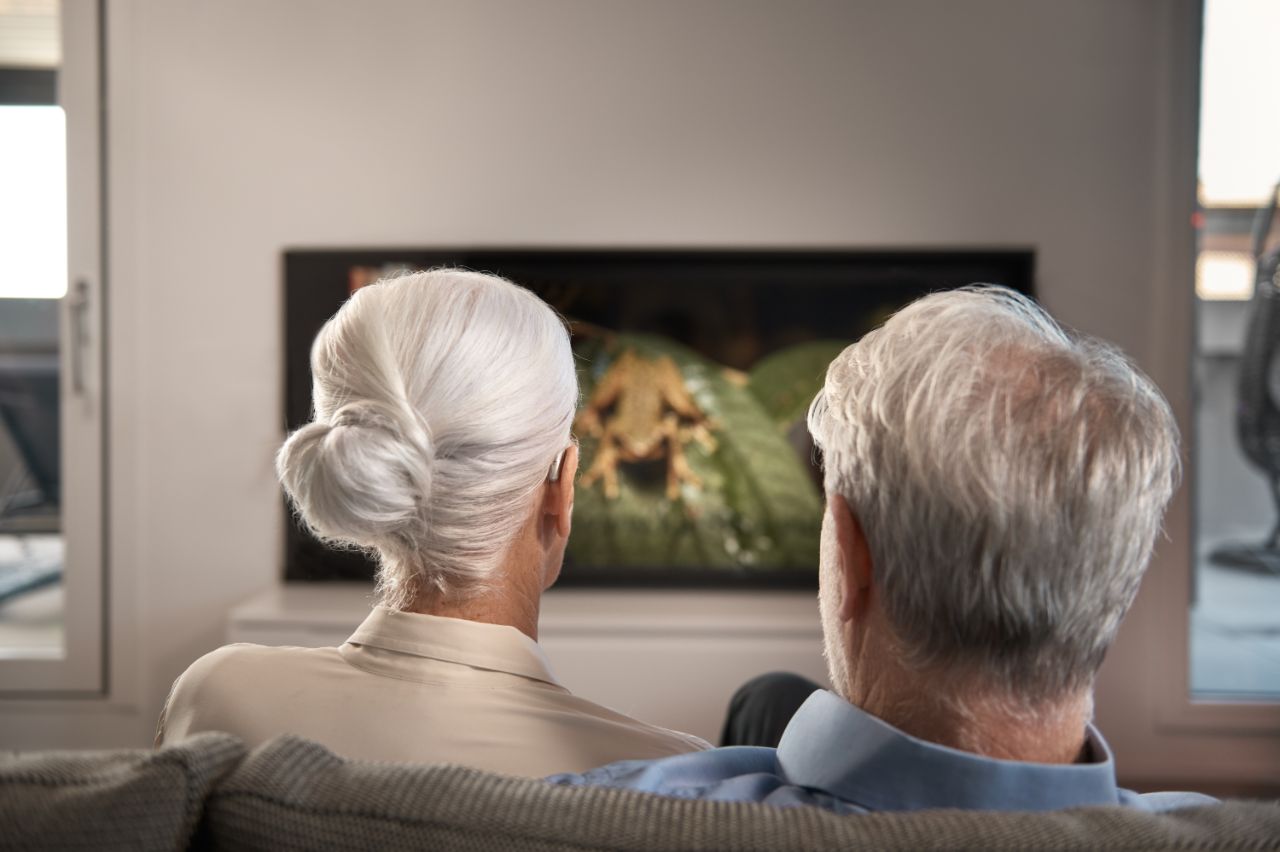 Casal sentado no sofá a ver televisão
