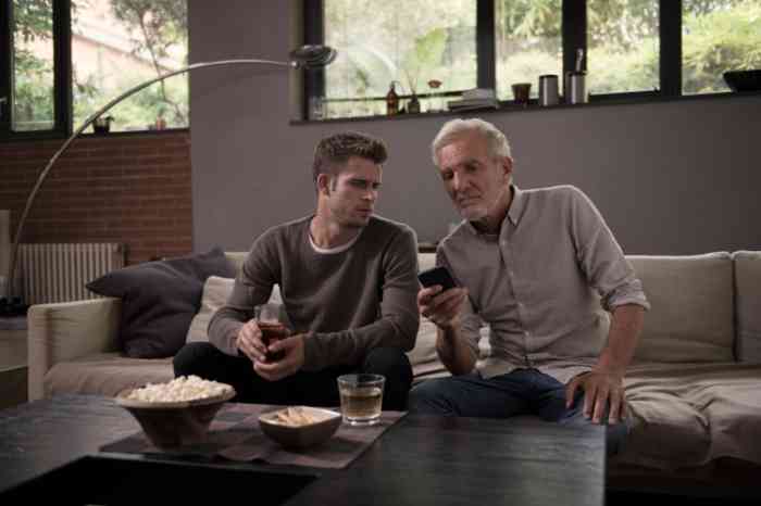 Dois homens sentados num sofá a olhar telemóvel