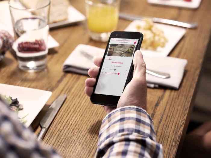 Senhor a ajustar o som do aparelho auditivo com o telemóvel
