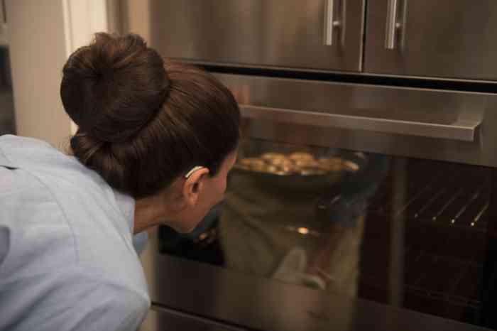 Senhora observa a comida que está no forno.