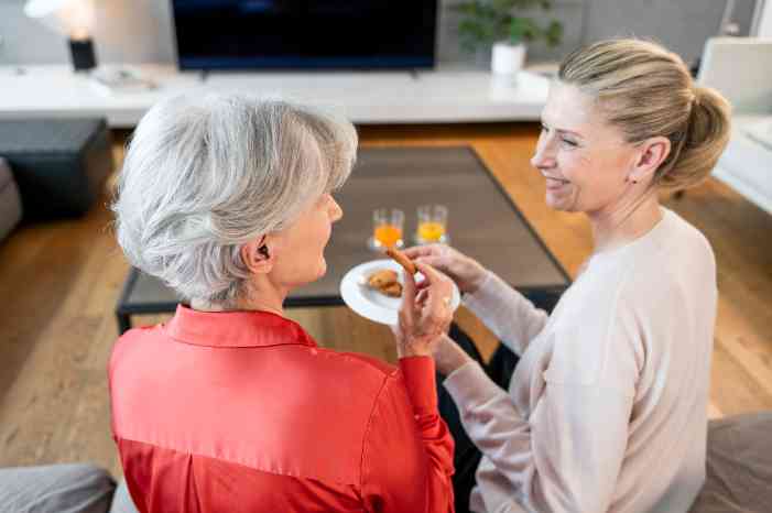 Mãe e filha, na sala, a comer e a conversar entre si