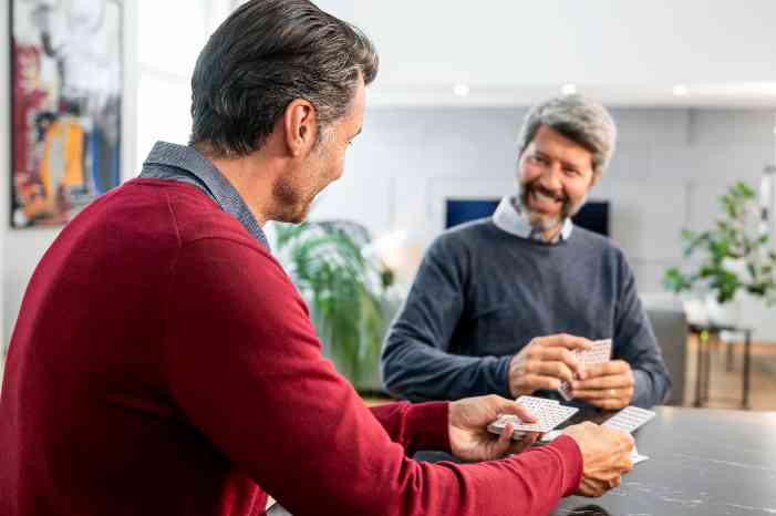 Casal com aparelho auditivo, a jogar às cartas na sala