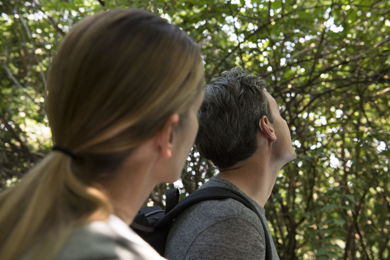 Homem e mulher com aparelho auditivo a passearem na natureza