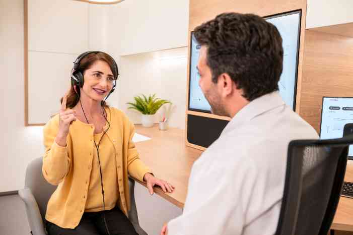 Audiologista num centro auditivo Minisom, a realizar um exame auditivo numa paciente