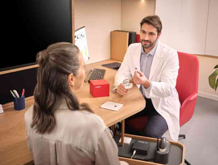 audiologista com ampli-mini na mão e cliente em frente