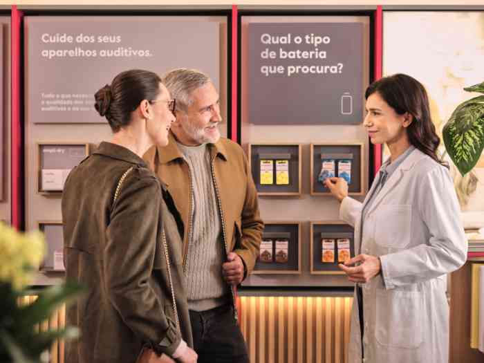 audiologista mostra pilhas para aparelhos auditivos a clientes
