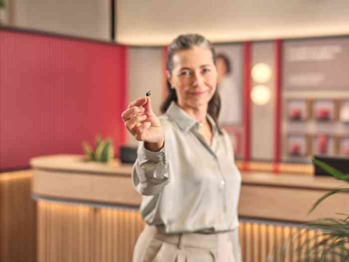 Cliente Minisom a segurar na mão o aparelho auditivo ampli-mini