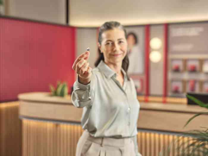 Cliente num centro auditivo a segurar ampli-mini nos dedos