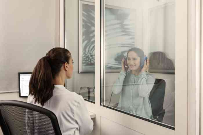 Audiologista e cliente numa cabine insonorizada a fazer teste auditivo