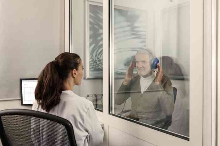 Homem a fazer teste auditivo numa cabine insonorizada