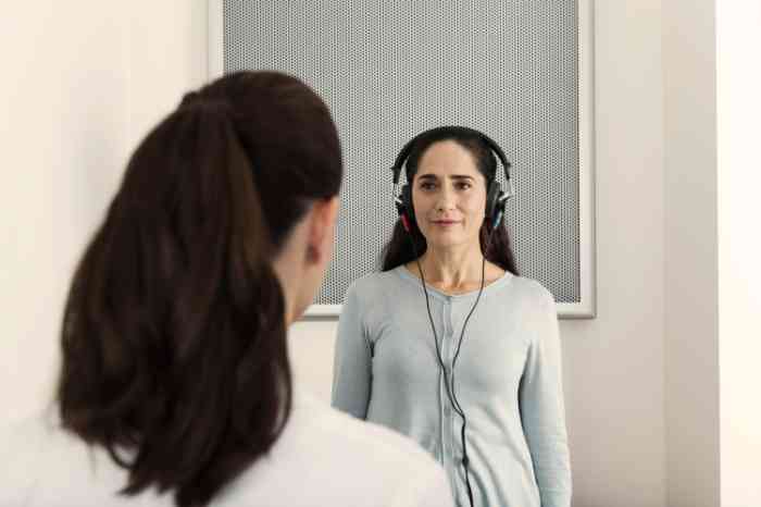 Cliente com uns headsets na cabeça durante a realização de um exame auditivo na Minisom