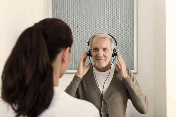 Audiologista a fazer teste auditivo a um homem com auscultadores na cabeça