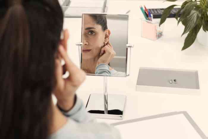 Cliente a experimentar aparelhos auditivos frente a espelho