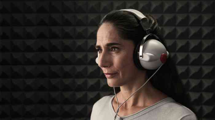 Senhora numa cabine com auscultadores realiza testes auditivos