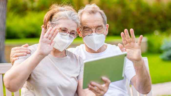 Casal de adultos com máscara a fazer videochamada atrav+es de tablet