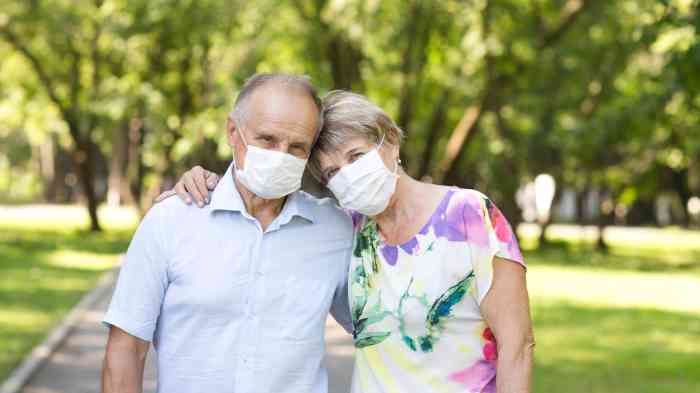 Casal com máscara na cara passeia num jardim