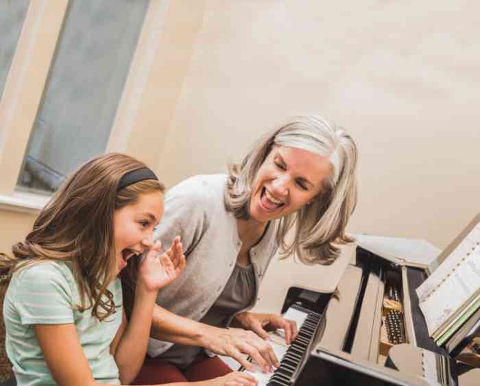 Avó e neta tocam piano de forma entusiasta e alegre.