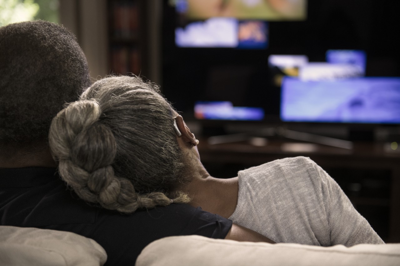 Casal desfruta de programa de TV com a ajuda auditiva de aparelhos auditivos da Minisom