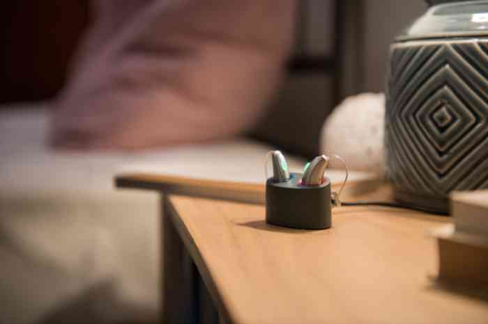 Aparelhos auditivos recarregáveis a carregar à noite em cima de uma mesa de cabeceira