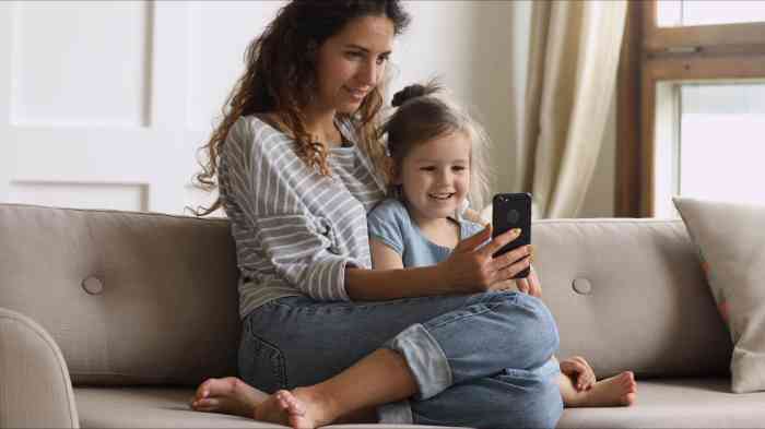 mãe e criança sentadas num sofá a olhar telemóvel