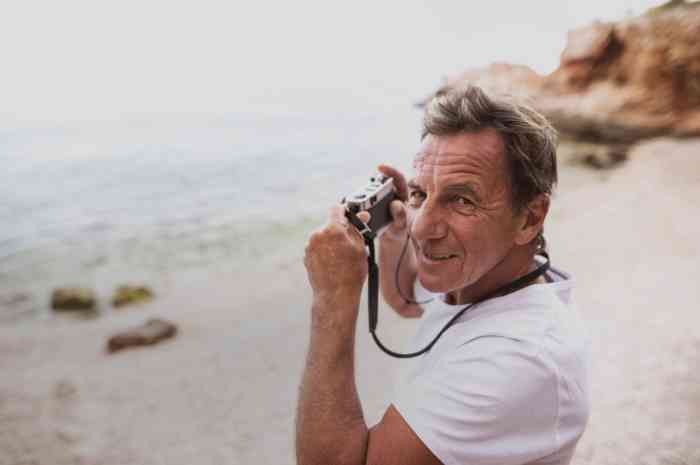 Homem com máquina fotográfica numa praia