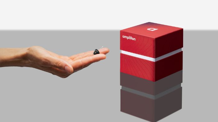 Caixa APE com uma mão a segurar aparelho auditivo