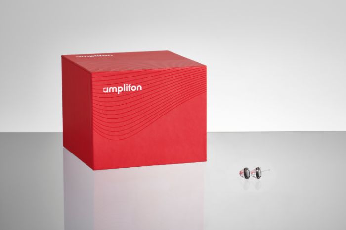 Cubo vermelho e caixa com o aparelho auditivo ampli-mini ao lado