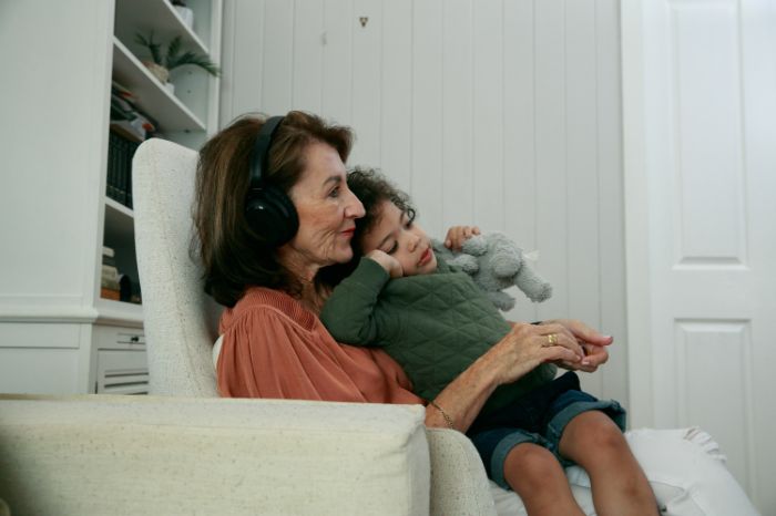 Mulher com o neto ao colo enquanto ouve música com os auscultadores