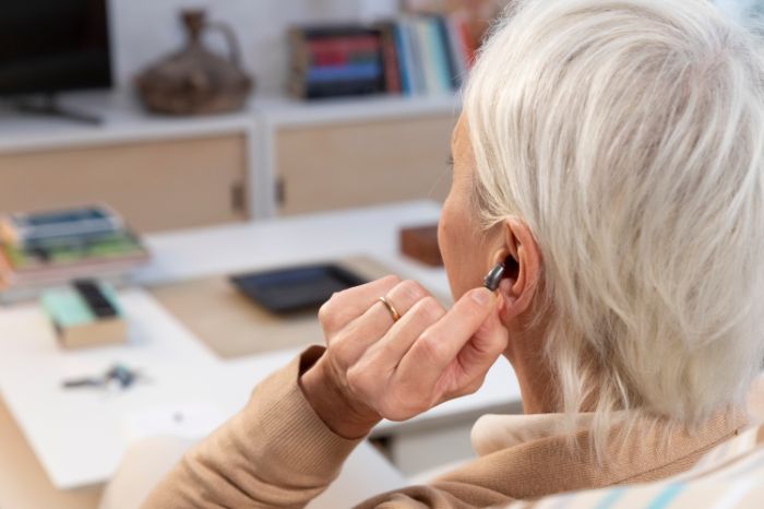 Senhora coloca aparelho auditivo intra no ouvido.