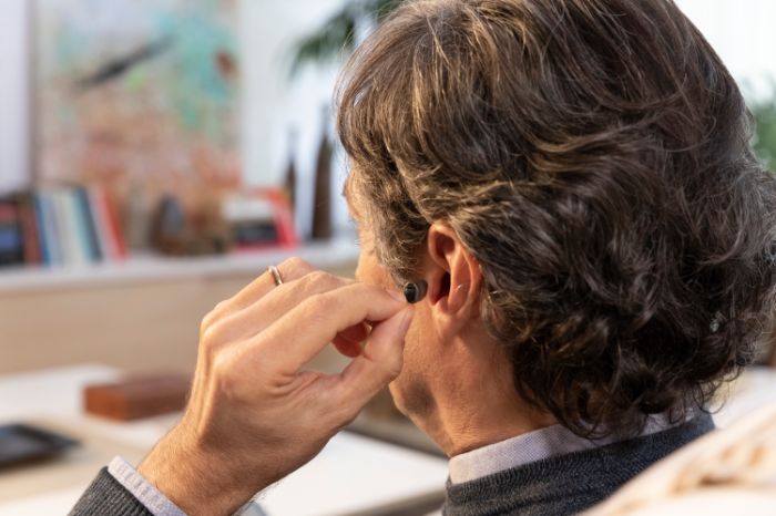 Senhor coloca no ouvido aparelho auditivo intra