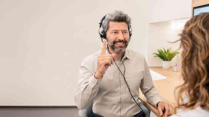 Homem com o dedo no ar, sinalizando ao audiologista que está a ouvir durante o teste auditivo na Minisom