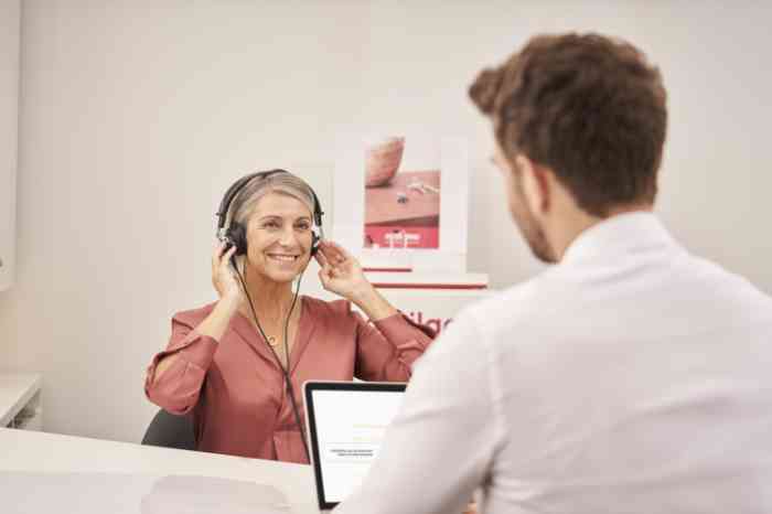 Audiologista com cliente num gabinete a fazer teste auditivo 